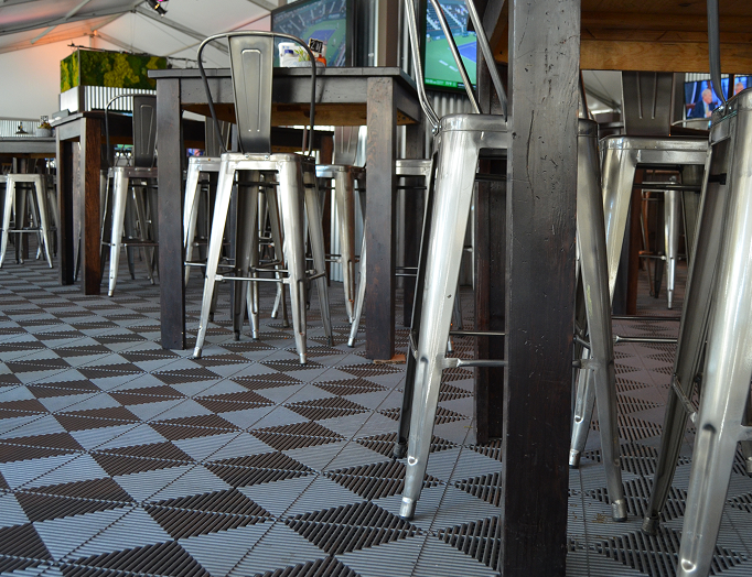 Bar area with metal stools and tables on a checkered floor.