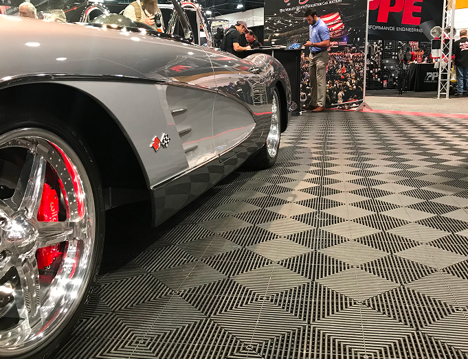 Silver sports car with red interior on a checkered floor at an auto show.