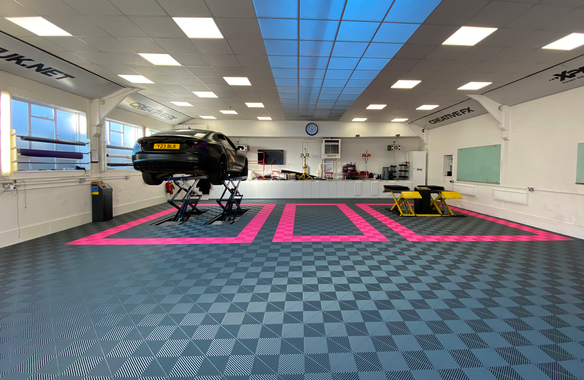 Automotive repair shop with a car on an lift and various tools and equipment.
