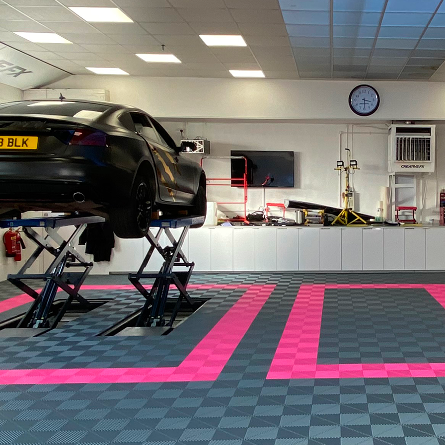 Car on a lift in a garage with a checkered floor